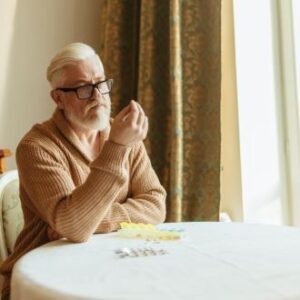 Mann betrachtet überlegend eine Tablette - Medikamenten-App | Pro Aging Welt
